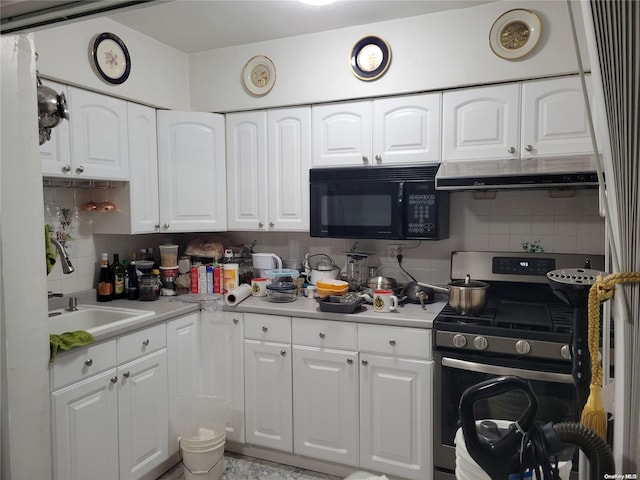 kitchen featuring tasteful backsplash, white cabinetry, sink, and stainless steel stove