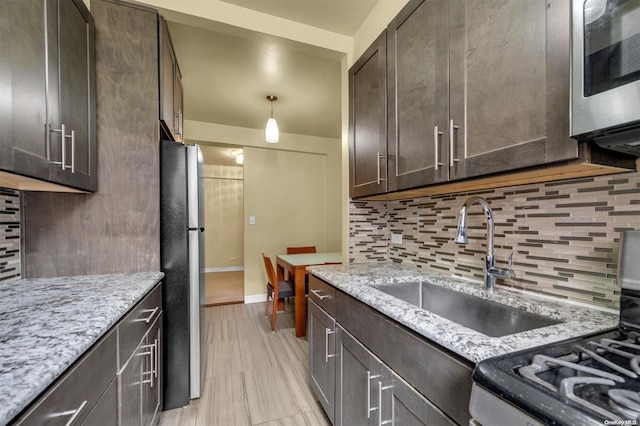 kitchen featuring stainless steel appliances, light stone countertops, sink, and dark brown cabinetry