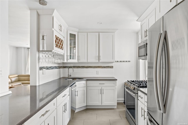 kitchen featuring white cabinetry, sink, hanging light fixtures, stainless steel appliances, and dark stone counters