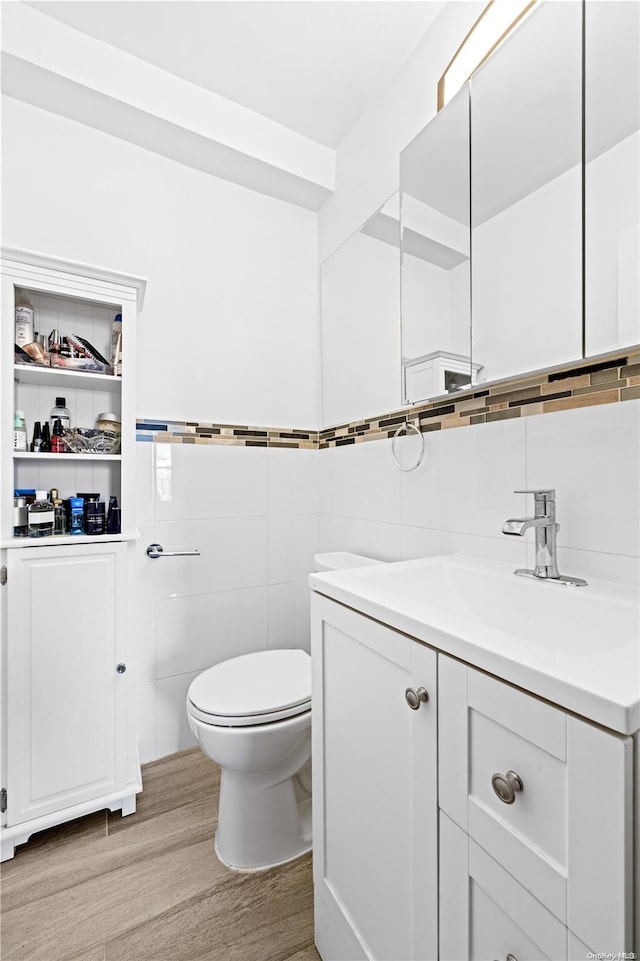 bathroom with vanity, toilet, wood-type flooring, and tile walls