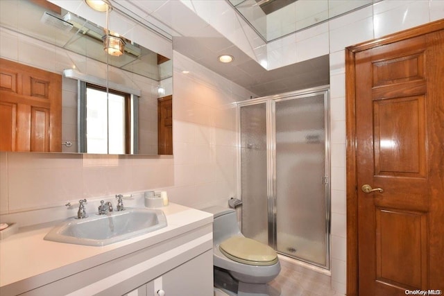 bathroom featuring vanity, toilet, a shower with shower door, and tile walls