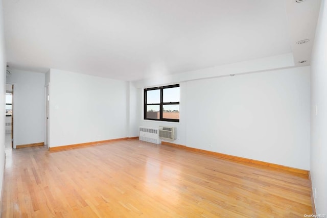 unfurnished living room featuring radiator, a wall mounted air conditioner, and light wood-type flooring