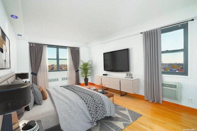 bedroom with wood-type flooring and an AC wall unit