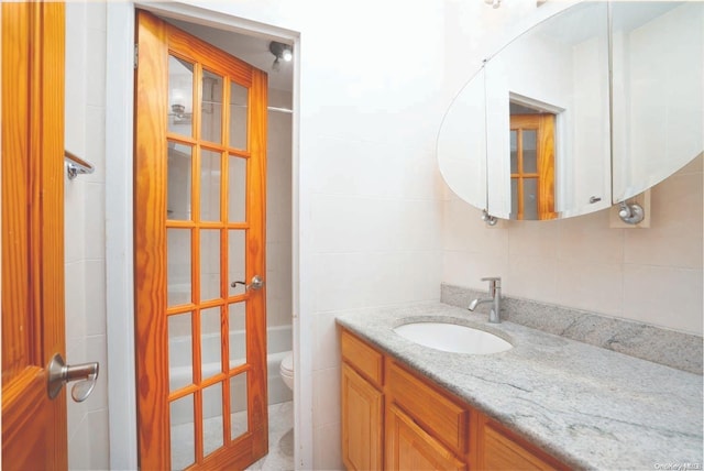 bathroom with vanity, toilet, tile walls, walk in shower, and tasteful backsplash