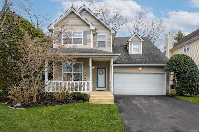 view of property featuring a garage, a front lawn, and covered porch