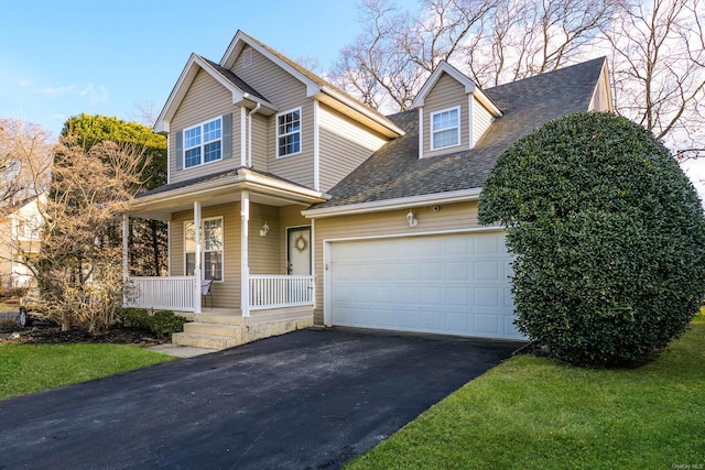 view of front of home featuring a porch, a garage, and a front yard