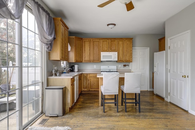 kitchen featuring white appliances, a kitchen bar, dark hardwood / wood-style flooring, and a kitchen island