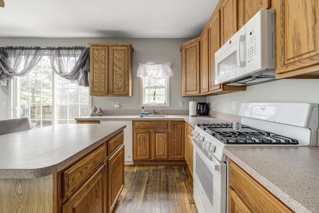 kitchen featuring white appliances, dark hardwood / wood-style floors, a center island, and sink