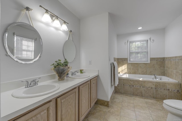 bathroom with tile patterned flooring, vanity, tiled bath, and toilet