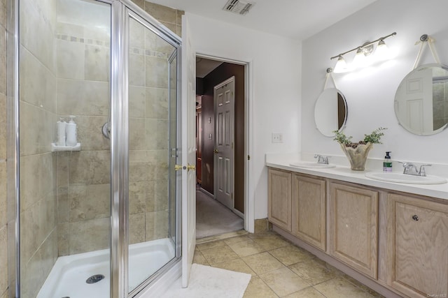 bathroom with a shower with door, vanity, and tile patterned floors