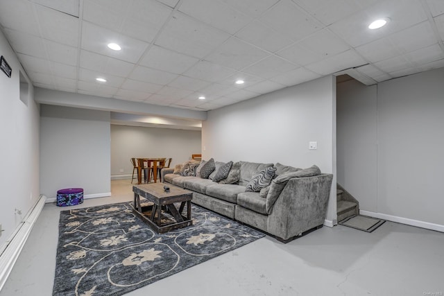 living room featuring a baseboard heating unit, a paneled ceiling, and concrete floors