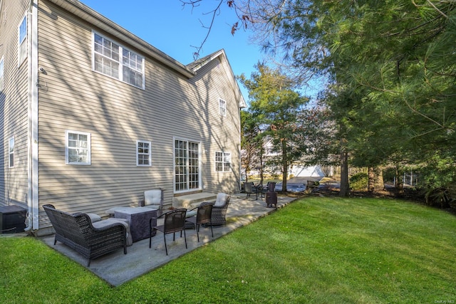 back of house featuring outdoor lounge area, a patio, and a lawn