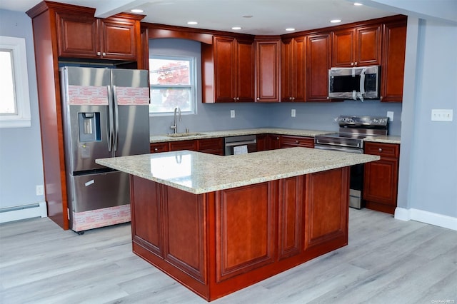 kitchen with light stone countertops, light wood-type flooring, sink, and appliances with stainless steel finishes