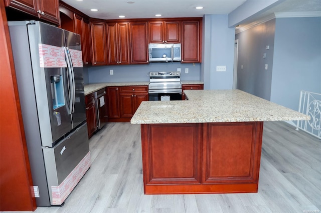 kitchen with a center island, light hardwood / wood-style flooring, ornamental molding, light stone counters, and stainless steel appliances