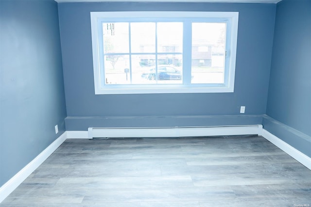 empty room featuring hardwood / wood-style flooring and baseboard heating