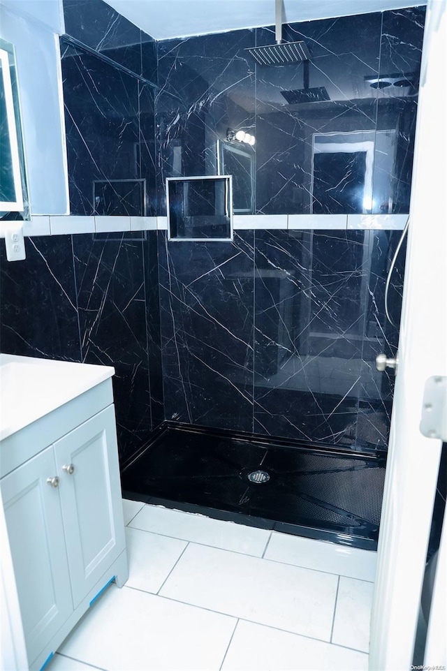 bathroom with tile patterned flooring, vanity, and tiled shower