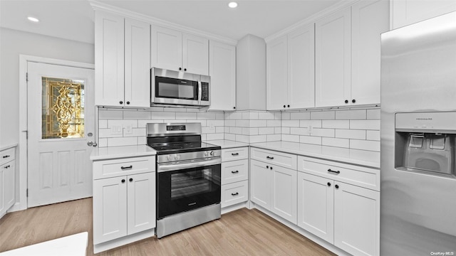 kitchen featuring backsplash, light hardwood / wood-style floors, white cabinetry, and stainless steel appliances