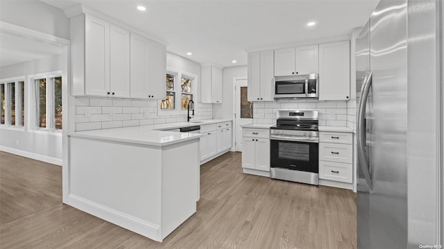 kitchen featuring appliances with stainless steel finishes, light hardwood / wood-style floors, white cabinetry, and a wealth of natural light