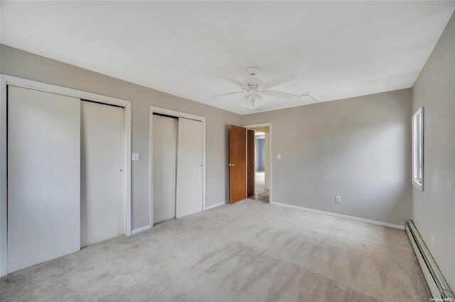 43 2nd St, Ronkonkoma, NY 11779 - unfurnished bedroom featuring a baseboard radiator, multiple closets, carpet floors, and a ceiling fan