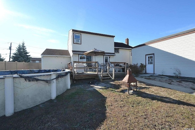 rear view of property with a lawn and a swimming pool side deck