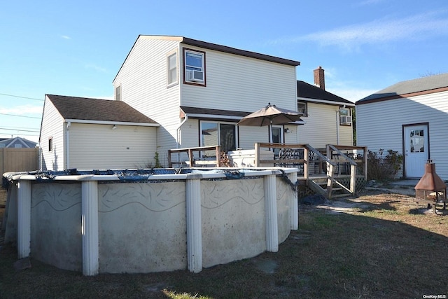 rear view of house with cooling unit and a pool side deck