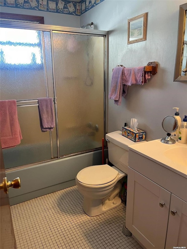 full bathroom with toilet, vanity, tile patterned floors, and bath / shower combo with glass door