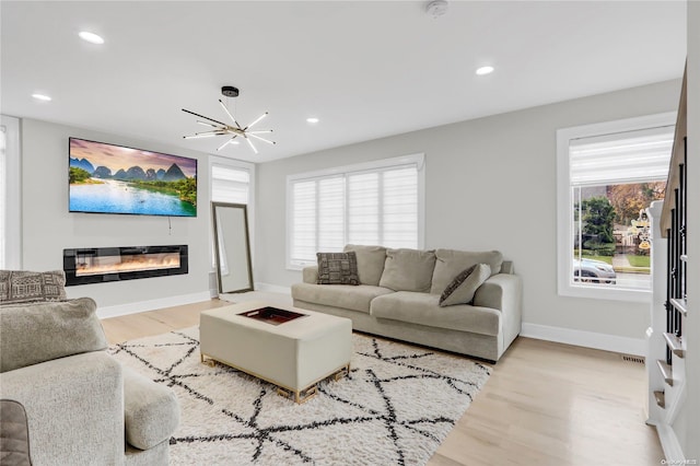 living room with a chandelier, light hardwood / wood-style flooring, and a healthy amount of sunlight