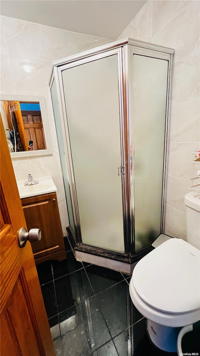 bathroom featuring vanity, tile patterned flooring, toilet, tile walls, and an enclosed shower