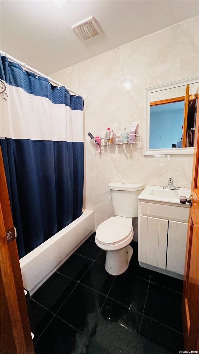 bathroom featuring tile patterned flooring, vanity, toilet, and tile walls