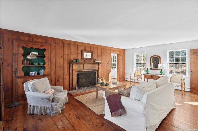 living room with hardwood / wood-style flooring, wooden walls, and baseboard heating