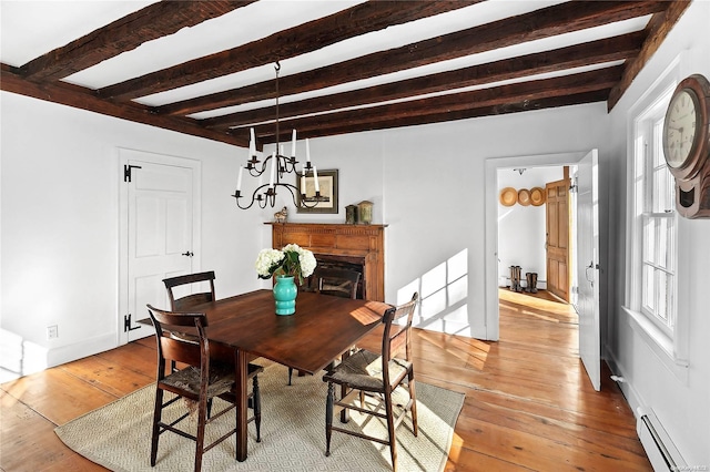 dining space with beamed ceiling, a baseboard radiator, and light wood-type flooring