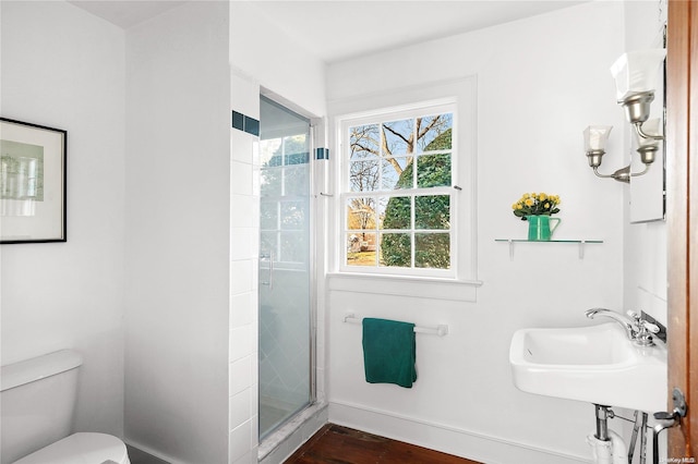 bathroom with wood-type flooring, a shower with shower door, sink, and toilet