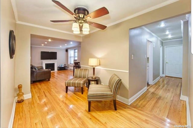 living area featuring ceiling fan, ornamental molding, and light wood-type flooring