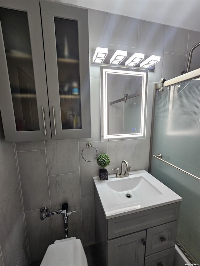 bathroom with an enclosed shower, vanity, tasteful backsplash, and tile walls