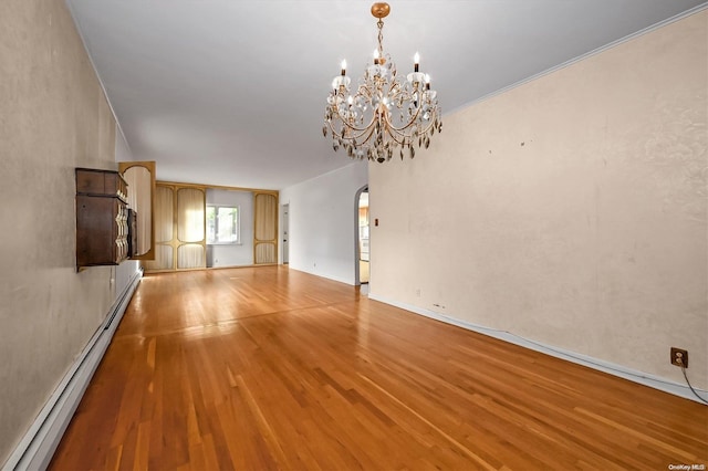 unfurnished room with a chandelier, light wood-type flooring, baseboard heating, and crown molding