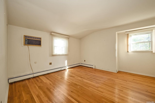 empty room featuring a wall unit AC, a healthy amount of sunlight, vaulted ceiling, and light wood-type flooring