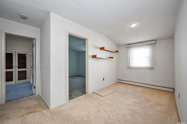 carpeted empty room featuring lofted ceiling and a baseboard heating unit