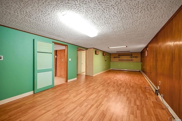 basement featuring wooden walls, light hardwood / wood-style flooring, crown molding, and a textured ceiling