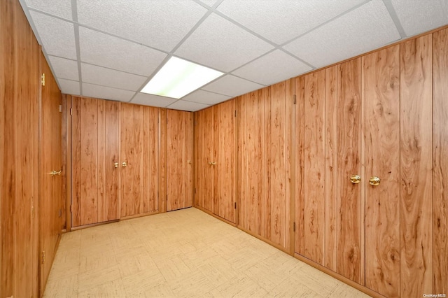 interior space featuring a paneled ceiling and wood walls