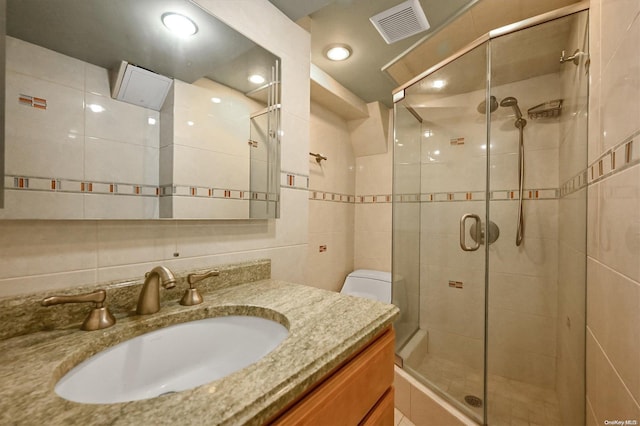 bathroom featuring an enclosed shower, vanity, toilet, and tile walls