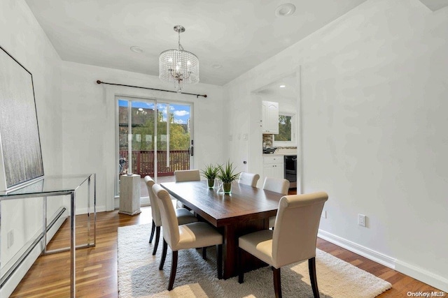 dining room featuring wine cooler, hardwood / wood-style floors, a notable chandelier, and a baseboard heating unit