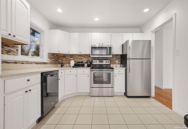 kitchen with tasteful backsplash, white cabinetry, sink, and appliances with stainless steel finishes