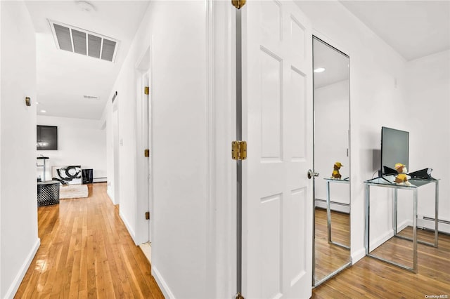 hallway with hardwood / wood-style flooring and a baseboard radiator