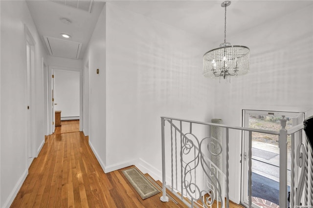 hall with a chandelier, wood-type flooring, and baseboard heating