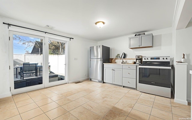 kitchen with gray cabinets, light tile patterned floors, and appliances with stainless steel finishes