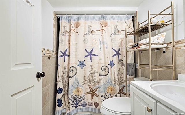 bathroom with curtained shower, vanity, tile walls, and toilet