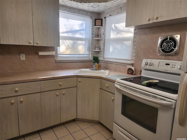 kitchen with light tile patterned floors, light countertops, a sink, and white range with electric cooktop