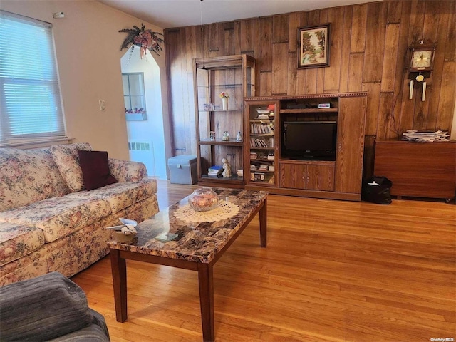 living area with wooden walls, light wood finished floors, and radiator