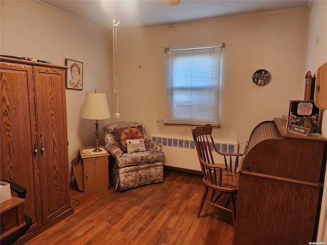 living area with ornamental molding, radiator, baseboards, and wood finished floors