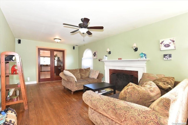 living room with a fireplace, ceiling fan, french doors, and dark wood-type flooring